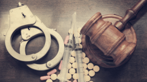 Handcuffs, syringes, miscellaneous pills on table